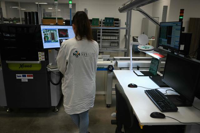 An employee works at an assembly line at Syselec group's factory, which produces printed circuit boards, in Castres, southwestern France, on February 17, 2026. (Photo by Lionel BONAVENTURE / AFP)