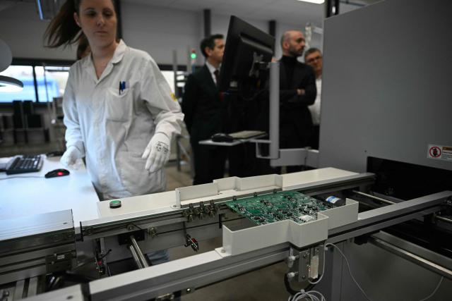 An employee works at an assembly line at Syselec group's factory, which produces printed circuit boards, in Castres, southwestern France, on February 17, 2026. (Photo by Lionel BONAVENTURE / AFP)