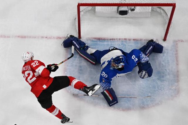 Italy's #20 Damian Clara makes a save from a shot played by Switzerland's #22 Nino Niederreiter during the men's qualification play-off ice hockey match between Switzerland and Italy during the Milano Cortina 2026 Winter Olympic Games at the Milano Rho Ice Hockey Arena in Milan, on February 17, 2026. (Photo by Piero CRUCIATTI / AFP)