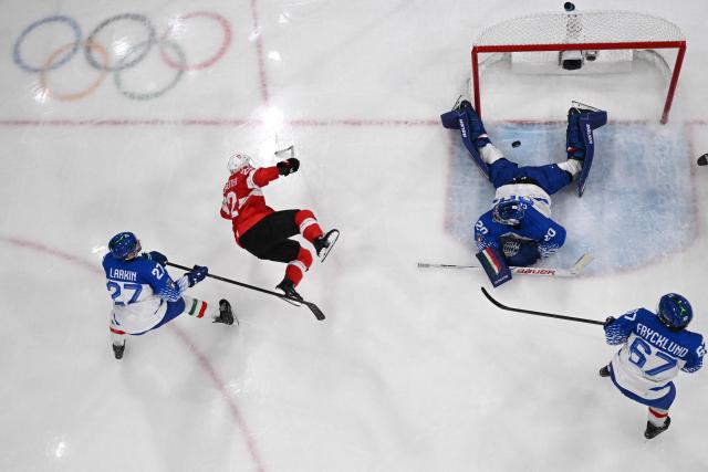 Italy's #20 Damian Clara makes a save from a shot played by Switzerland's #22 Nino Niederreiter during the men's qualification play-off ice hockey match between Switzerland and Italy during the Milano Cortina 2026 Winter Olympic Games at the Milano Rho Ice Hockey Arena in Milan, on February 17, 2026. (Photo by Piero CRUCIATTI / AFP)