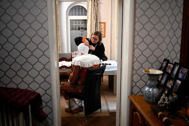 A carnival goer gets help dressing up as Gilles de Binche, the oldest and principal participants in the Carnival of Binche, before the parade in Binche on February 17, 2026. The Binche Carnival tradition is one of the most ancient and representative of Wallonia and inscribed in 2008 on the Representative List of the Intangible Cultural Heritage of Humanity by UNESCO. (Photo by JOHN THYS / AFP)