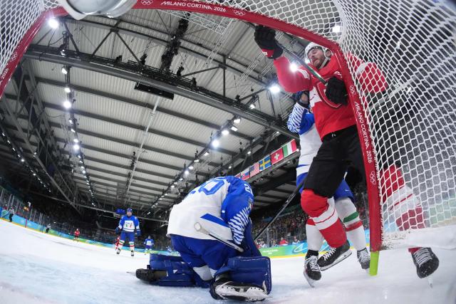 Italy's #37 Phil Pietroniro pushes Switzerland's #88 Christoph Bertschy into the goal posts during the men's qualification play-off ice hockey match between Switzerland and Italy during the Milano Cortina 2026 Winter Olympic Games at the Milano Rho Ice Hockey Arena in Milan, on February 17, 2026. (Photo by Tao Xiyi / POOL / AFP)