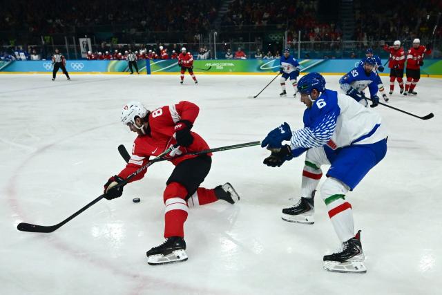 Italy's #06 Jason Seed fights for the puck with Switzerland's #88 Christoph Bertschy during the men's qualification play-off ice hockey match between Switzerland and Italy during the Milano Cortina 2026 Winter Olympic Games at the Milano Rho Ice Hockey Arena in Milan, on February 17, 2026. (Photo by PIERO CRUCIATTI / AFP)