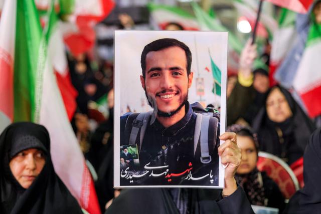 A woman holds a picture of a slain person during a memorial ceremony marking the 40th day of mourning for victims of "terrorism" killed in previous anti-government protests in Iran, at the Tehran Musalla on February 17, 2026. (Photo by ATTA KENARE / AFP)