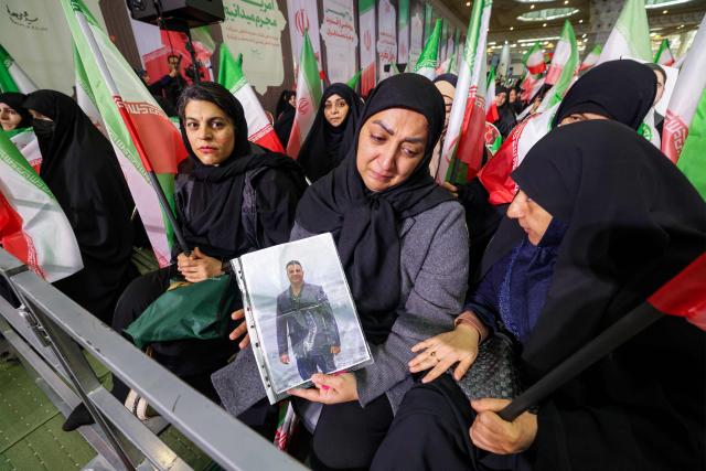 A woman holds a picture of a slain person during a memorial ceremony marking the 40th day of mourning for victims of "terrorism" killed in previous anti-government protests in Iran, at the Tehran Musalla on February 17, 2026. (Photo by ATTA KENARE / AFP)