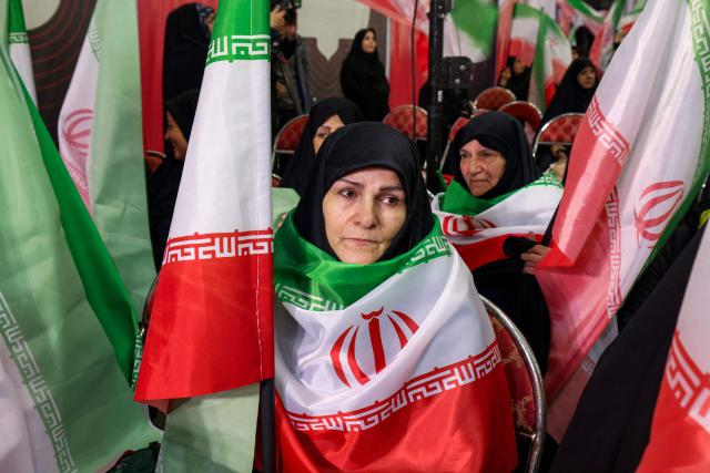 Women draped in Iranian flags attend a memorial ceremony marking the 40th day of mourning for victims of "terrorism" killed in previous anti-government protests in Iran, at the Tehran Musalla on February 17, 2026. (Photo by ATTA KENARE / AFP)