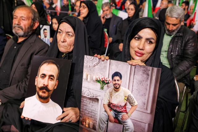 Women hold pictures of slain persons during a memorial ceremony marking the 40th day of mourning for victims of "terrorism" killed in previous anti-government protests in Iran, at the Tehran Musalla on February 17, 2026. (Photo by ATTA KENARE / AFP)