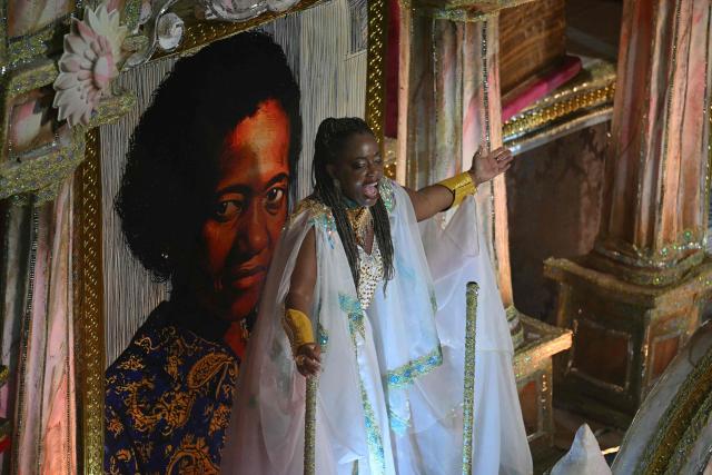 A reveller of the Unidos da Tijuca samba school performs in front of an image depicting Brazilian outskirts memoirist Carolina Maria de Jesus during the second night of the Rio Carnival at the Marques de Sapucai Sambadrome in Rio de Janeiro, Brazil, early on February 17, 2026. (Photo by Mauro PIMENTEL / AFP)