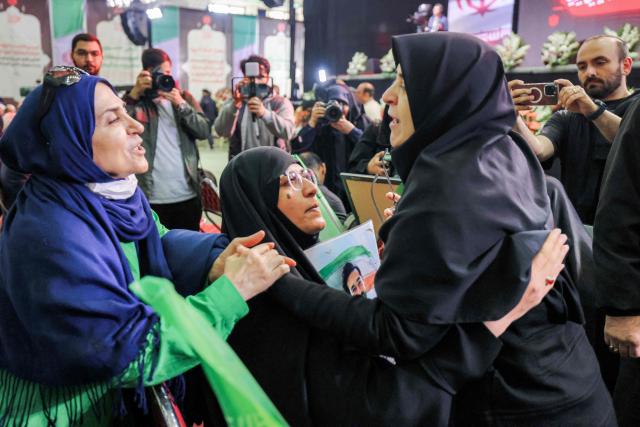 Iran's government spokesperson Fatemeh Mohajerani (R) embraces the relative of a victim during a memorial ceremony marking the 40th day of mourning for victims of "terrorism" killed in previous anti-government protests in Iran, at the Tehran Musalla on February 17, 2026. (Photo by ATTA KENARE / AFP)