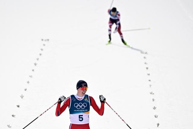 Norway's Jens Luraas Oftebro reacts after crossing the finish to win overall gold, ahead of Austria's Johannes Lamparter (Rear) in the cross-country event of the nordic combined individual Gundersen large hill/10km at Tesero Cross Country Stadium at Lago di Tesero (Val di Fiemme) during the Milano Cortina 2026 Winter Olympic Games on February 17, 2026. (Photo by Tobias SCHWARZ / AFP)