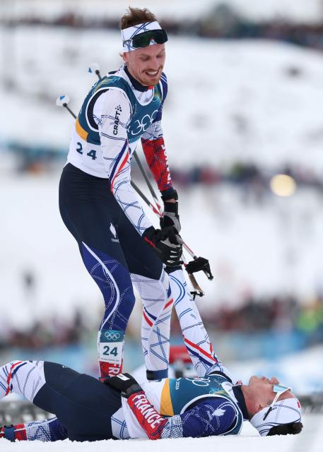 France's Mael Tyrode lifts up France's Marco Heinis after they competed in the cross-country event of the nordic combined individual Gundersen large hill/10km at Tesero Cross Country Stadium at Lago di Tesero (Val di Fiemme) during the Milano Cortina 2026 Winter Olympic Games on February 17, 2026. (Photo by Anne-Christine POUJOULAT / AFP)
