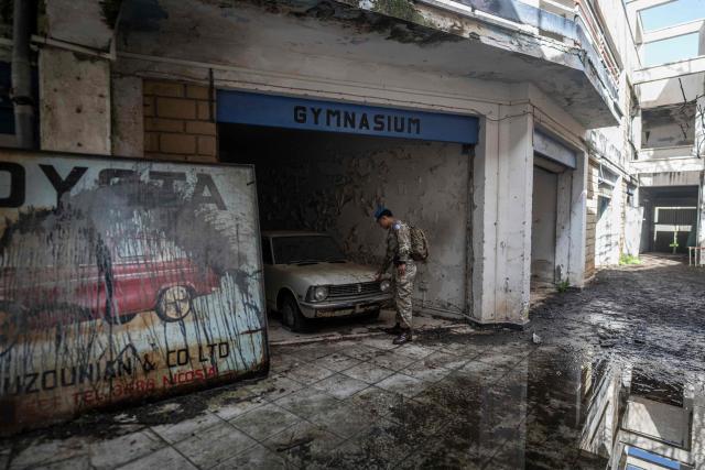 TOPSHOT - Lance Corporal Robertsing Neyong Limbu of the UN Peacekeeping Force in Cyprus (UNFICYP), from the British Army’s 1st Battalion Coldstream Guards, No. 2 Company, inspects a car in an abandoned showroom while patrolling the buffer zone separating the internationally recognized Republic of Cyprus and the breakaway Turkish Republic of Northern Cyprus in the divided capital Nicosia on February 17, 2026. Cyprus has been divided since 1974, when a Turkish invasion followed a coup in Nicosia backed by Greece’s then military junta. The Turkish Republic of Northern Cyprus, declared in 1983, is recognized only by Ankara, while the internationally recognized Republic of Cyprus — a member of the European Union — controls the island’s majority Greek Cypriot south. There are currently nine crossings along the UN-patrolled Green Line separating the two sides, and calls have grown for additional crossings along the 180-kilometre (110-mile) buffer zone to ease access for people in remote areas. Thousands cross daily for work, education or medical care using the crossings operational since 2003, while reunification efforts brokered by the United Nations have remained frozen since talks collapsed in 2017. (Photo by Jewel SAMAD / AFP)