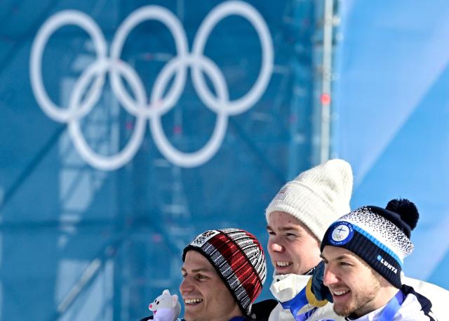 (From L) Silver medalist Austria's Johannes Lamparter, gold medallist Norway's Jens Luraas Oftebro and bronze medallist Finland's Ilkka Herola celebrate on the podium following the nordic combined individual Gundersen large hill/10km event at Tesero Cross Country Stadium at Lago di Tesero (Val di Fiemme) during the Milano Cortina 2026 Winter Olympic Games on February 17, 2026. (Photo by Tobias SCHWARZ / AFP)