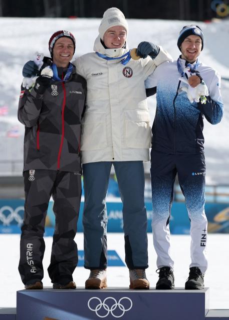 (From L) Silver medalist Austria's Johannes Lamparter, gold medallist Norway's Jens Luraas Oftebro and bronze medallist Finland's Ilkka Herola celebrate on the podium following the nordic combined individual Gundersen large hill/10km event at Tesero Cross Country Stadium at Lago di Tesero (Val di Fiemme) during the Milano Cortina 2026 Winter Olympic Games on February 17, 2026. (Photo by Anne-Christine POUJOULAT / AFP)