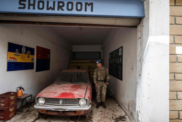 Lance Corporal Robertsing Neyong Limbu of the UN Peacekeeping Force in Cyprus (UNFICYP), from the British Army’s 1st Battalion Coldstream Guards, No. 2 Company, inspects a car in an abandoned showroom while patrolling the buffer zone separating the internationally recognized Republic of Cyprus and the breakaway Turkish Republic of Northern Cyprus in the divided capital Nicosia on February 17, 2026. Cyprus has been divided since 1974, when a Turkish invasion followed a coup in Nicosia backed by Greece’s then military junta. The Turkish Republic of Northern Cyprus, declared in 1983, is recognized only by Ankara, while the internationally recognized Republic of Cyprus — a member of the European Union — controls the island’s majority Greek Cypriot south. There are currently nine crossings along the UN-patrolled Green Line separating the two sides, and calls have grown for additional crossings along the 180-kilometre (110-mile) buffer zone to ease access for people in remote areas. Thousands cross daily for work, education or medical care using the crossings operational since 2003, while reunification efforts brokered by the United Nations have remained frozen since talks collapsed in 2017. (Photo by Jewel SAMAD / AFP)
