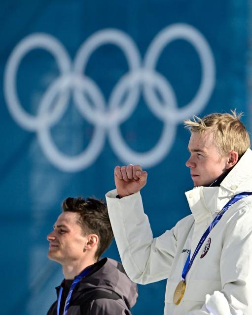 Gold medallist Norway's Jens Luraas Oftebro (R) and silver medallist Austria's Johannes Lamparter celebrate on the podium following the nordic combined individual Gundersen large hill/10km event at Tesero Cross Country Stadium at Lago di Tesero (Val di Fiemme) during the Milano Cortina 2026 Winter Olympic Games on February 17, 2026. (Photo by Tobias SCHWARZ / AFP)