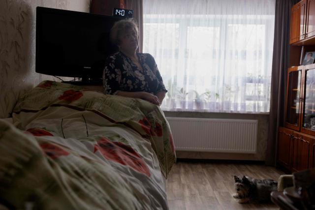 Olena Grygorenko stands by her husband Anatoli Kuchynsky's bed in Chernihiv on February 12, 2026, amid the Russian invasion of Ukraine. Olena Grygorenko has barely left her Chernigiv flat in the past weeks. Every time a blackout hits the city, she rushes to her husband's bedside to plug his life support machine into its back-up batteries. Bedridden, completely paralysed and connected 24/7 to a life support machine, her husband Anatoli Kuchynsky suffers amyotrophic lateral sclerosis (ALS) - an incurable degenerative nerve disease. Russia's incessant strikes on Ukraine's energy grid over the last month have made their fight against the condition even more perilous. (Photo by Tetiana DZHAFAROVA / AFP)