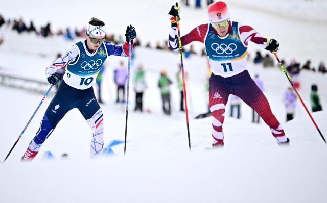 France's Marco Heinis (L) and Austria's Stefan Rettenegger compete in the cross-country event of the nordic combined individual Gundersen large hill/10km at Tesero Cross Country Stadium at Lago di Tesero (Val di Fiemme) during the Milano Cortina 2026 Winter Olympic Games on February 17, 2026. (Photo by Tobias SCHWARZ / AFP)