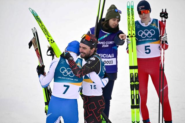 (From L) Overall bronze medallist Finland's Ilkka Herola, Germany's Johannes Rydzek and overall gold medallist Norway's Jens Luraas Oftebro (R) react after competing in the cross-country event of the nordic combined individual Gundersen large hill/10km at Tesero Cross Country Stadium at Lago di Tesero (Val di Fiemme) during the Milano Cortina 2026 Winter Olympic Games on February 17, 2026. (Photo by Tobias SCHWARZ / AFP)