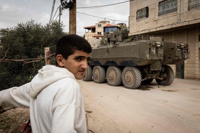 A Palestinian man looks on next to an Israeli armored vehicle during a military raid in  al-Yamun town west of Jenin in the occupied West Bank on February 17, 2026. (Photo by JOHN WESSELS / AFP)