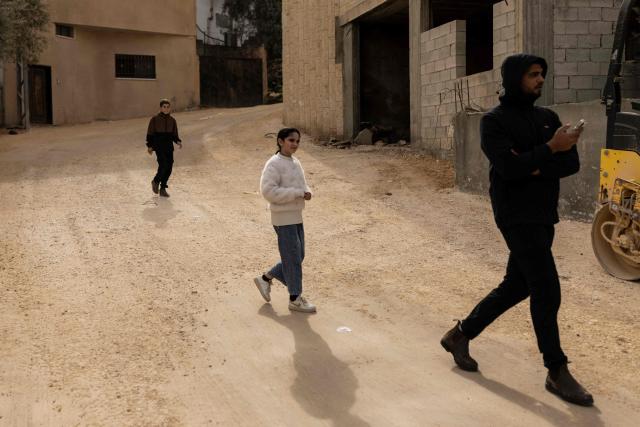 Palestinians walk down a road to look at an ongoing Israeli military raid in al-Yamun town west of Jenin in the occupied West Bank on February 17, 2026. (Photo by JOHN WESSELS / AFP)