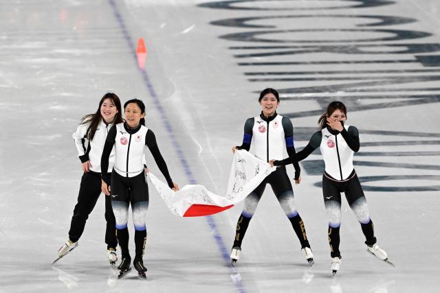(From L) Japan's Momoka Horikawa, Japan's Miho Takagi, Japan's Hana Noake and Japan's Ayano Sato celebrate with a Japanese flag after winning bronze in the speed skating women's team pursuit final during the Milano Cortina 2026 Winter Olympic Games at Milano Speed Skating Stadium in Milan on February 17, 2026. (Photo by Daniel MUNOZ / AFP)