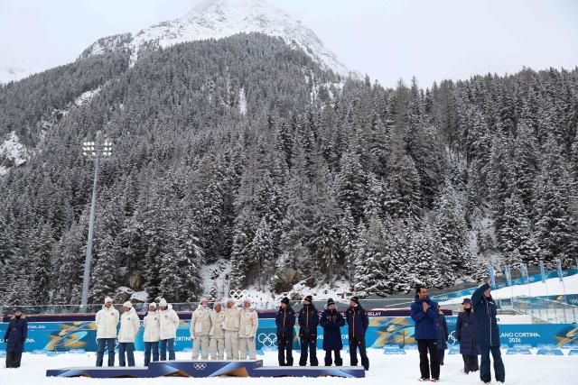 French biathlon champion Martin Fourcade (2nd R) applauds as (From L) Silver medallists Silver medallists Norway's Vetle Sjaastad Christiansen, Norway's Sturla Holm Laegreid, Norway's Johan-Olav Botn and Norway's Martin Uldal, gold medallists France's Eric Perrot, France's Quentin Fillon Maillet, France's Emilien Jacquelin and France's Fabien Claude and bronze medallists Sweden's Sebastian Samuelsson, Sweden's Martin Ponsiluoma, Sweden's Jesper Nelin and Sweden's Viktor Brandt celebrate on the podium after competing in the men's biathlon 4 x 7,5km relay event during the Milano Cortina 2026 Winter Olympic Games at the Anterselva Biathlon Arena (Sudtirol Arena) in Anterselva (Val Pusteria) on February 17, 2026. (Photo by Franck FIFE / AFP)
