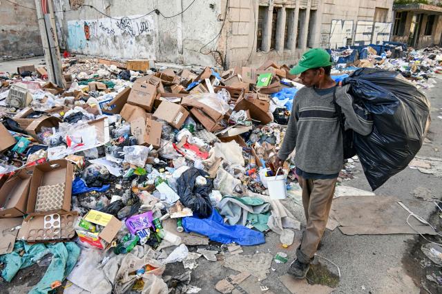 A man walks past garbage piled up on a street in Havana on February 17, 2026. (Photo by YAMIL LAGE / AFP)