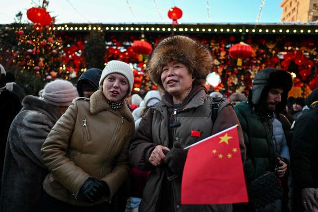 A tourist holding a Chinese flag is seen during the Lunar New Year of the Horse celebrations at Moscow's Manezhnaya Square on February 17, 2026. (Photo by Hector RETAMAL / AFP)