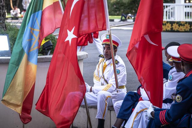 A soldier in ceremonial uniform rests holding the national flags of Turkiye and Ethiopia as he wait the departure of the countries two leaders from the National Palace in Addis Ababa on February 17, 2026. (Photo by Marco Simoncelli / AFP)