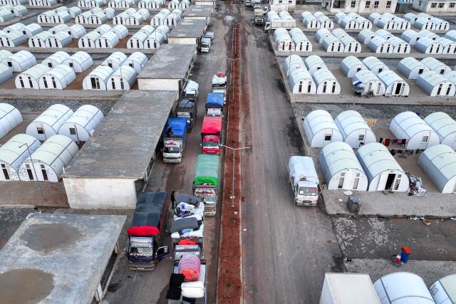 This aerial view shows vehicles by the tent shelters for people arriving from the Hol camp in eastern Syria, at the Akbaran camp near Akhtarin, in the north of Aleppo province, on February 17, 2026. Syria began evacuating remaining residents of Al-Hol camp, which long housed relatives of suspected Islamic State group fighters, as it empties the formerly Kurdish-controlled facility, two officials told AFP. Al-Hol had been Syria's largest camp housing relatives of suspected IS fighters before it was taken over by government forces from its Kurdish administrators. (Photo by OMAR HAJ KADOUR / AFP)