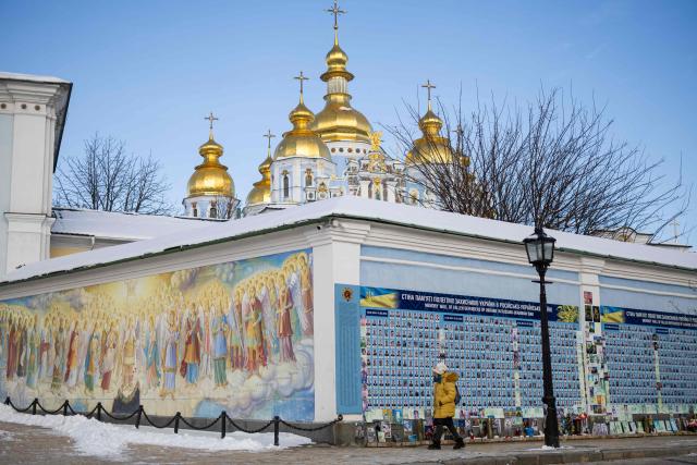 A woman walks alongside The Wall of Remembrance of the Fallen for Ukraine in Kyiv on February 17, 2026, amid the Russian invasion of Ukraine. (Photo by HENRY NICHOLLS / AFP)