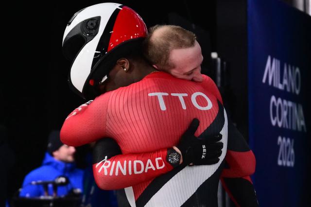 Trinidad and Tobago's Axel Brown and Trinidad and Tobago's De Aundre John hug each other after competing in the bobsleigh men's 2-man heat 3 at Cortina Sliding Centre during the Milano Cortina 2026 Winter Olympic Games in Cortina d'Ampezzo on February 17, 2026. (Photo by Stefano RELLANDINI / AFP)