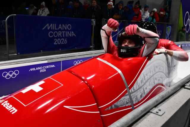 Switzerland's Cedric Follador and Switzerland's Luca Rolli react after competing in the bobsleigh men's 2-man heat 4 at Cortina Sliding Centre during the Milano Cortina 2026 Winter Olympic Games in Cortina d'Ampezzo on February 17, 2026. (Photo by Stefano RELLANDINI / AFP)