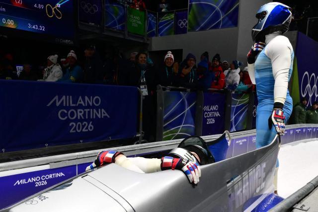 France's Romain Heinrich and France's Dorian Hauterville (R) react after competing in the bobsleigh men's 2-man heat 4 at Cortina Sliding Centre during the Milano Cortina 2026 Winter Olympic Games in Cortina d'Ampezzo on February 17, 2026. (Photo by Stefano RELLANDINI / AFP)