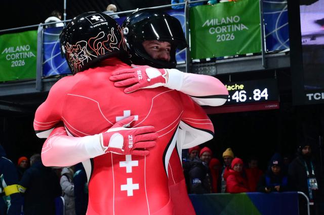 Switzerland's Michael Vogt and Switzerland's Amadou David Ndiaye celebrate after competing in the bobsleigh men's 2-man heat 4 at Cortina Sliding Centre during the Milano Cortina 2026 Winter Olympic Games in Cortina d'Ampezzo on February 17, 2026. (Photo by Stefano RELLANDINI / AFP)
