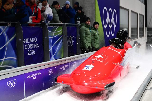 Switzerland's Michael Vogt and Switzerland's Amadou David Ndiaye celebrate after competing in the bobsleigh men's 2-man heat 4 at Cortina Sliding Centre during the Milano Cortina 2026 Winter Olympic Games in Cortina d'Ampezzo on February 17, 2026. (Photo by Stefano RELLANDINI / AFP)