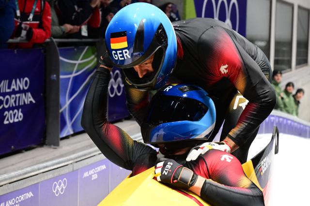 Germany's Johannes Lochner and Germany's Georg Fleischhauer celebrate after winning the bobsleigh men's 2-man heat 4 at Cortina Sliding Centre during the Milano Cortina 2026 Winter Olympic Games in Cortina d'Ampezzo on February 17, 2026. (Photo by Stefano RELLANDINI / AFP)