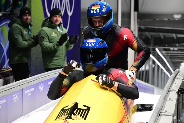 Germany's Johannes Lochner and Germany's Georg Fleischhauer celebrate after winning the bobsleigh men's 2-man heat 4 at Cortina Sliding Centre during the Milano Cortina 2026 Winter Olympic Games in Cortina d'Ampezzo on February 17, 2026. (Photo by Stefano RELLANDINI / AFP)