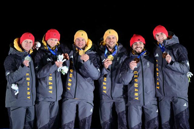(From L) Silver medallists Germany's Francesco Friedrich and Germany's Alexander Schueller, gold medallists Germany's Johannes Lochner and Germany's Georg Fleischhauer and bronze medallists Germany's Adam Ammour and Germany's Alexander Schaller celebrate on the podium after competing in the bobsleigh men's 2-man event at Cortina Sliding Centre during the Milano Cortina 2026 Winter Olympic Games in Cortina d'Ampezzo on February 17, 2026. (Photo by Stefano RELLANDINI / AFP)