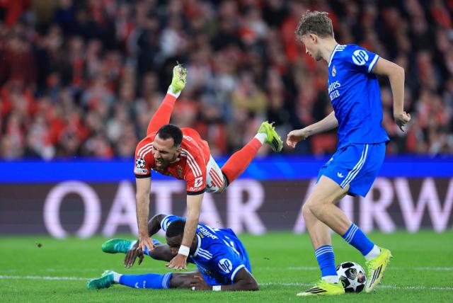 SL Benfica's Greek forward #14 Vangelis Pavlidis falls next to Real Madrid's German defender #22 Antonio Ruediger during the UEFA Champions League knockout round play-off first leg football match between SL Benfica and Real Madrid CF at Estadio da Luz in Lisbon on February 17, 2026. (Photo by PATRICIA DE MELO MOREIRA / AFP)