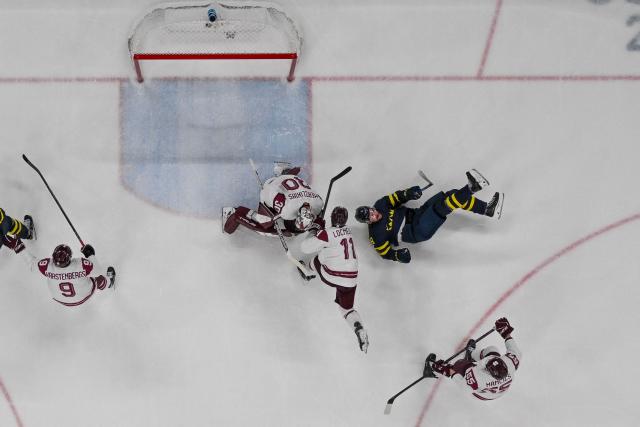 Sweden's #09 Filip Forsberg (R) goes down as he vies for the puck with Latvia's #11 Dans Locmelis during the men's qualification play-off ice hockey match between Sweden and Latvia at the Milano Santagiulia Ice Hockey Arena during the Milano Cortina 2026 Winter Olympic Games in Milan, on February 17, 2026. (Photo by Alexander NEMENOV / AFP)