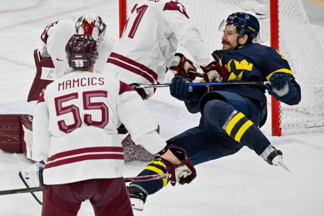 Sweden's #09 Filip Forsberg (R) goes down as he vies for the puck during the men's qualification play-off ice hockey match between Sweden and Latvia at the Milano Santagiulia Ice Hockey Arena during the Milano Cortina 2026 Winter Olympic Games in Milan, on February 17, 2026. (Photo by Alexander NEMENOV / AFP)