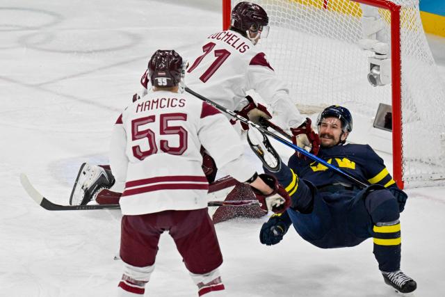 Sweden's #09 Filip Forsberg (R) goes down as he vies for the puck with Latvia's #11 Dans Locmelis during the men's qualification play-off ice hockey match between Sweden and Latvia at the Milano Santagiulia Ice Hockey Arena during the Milano Cortina 2026 Winter Olympic Games in Milan, on February 17, 2026. (Photo by Alexander NEMENOV / AFP)