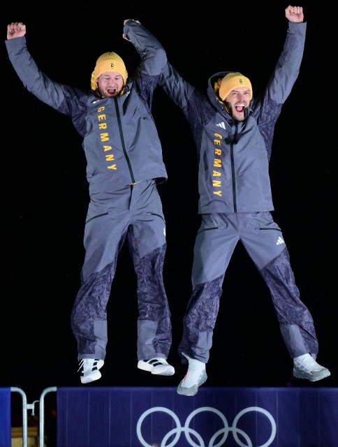 Gold medallists Germany's Johannes Lochner and Germany's Georg Fleischhauer celebrate on the podium after competing in the bobsleigh men's 2-man event at Cortina Sliding Centre during the Milano Cortina 2026 Winter Olympic Games in Cortina d'Ampezzo on February 17, 2026. (Photo by Stefano RELLANDINI / AFP)
