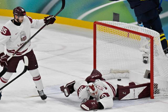 Latvia's #30 Elvis Merzlikins (R) concedes their third goal during the men's qualification play-off ice hockey match between Sweden and Latvia at the Milano Santagiulia Ice Hockey Arena during the Milano Cortina 2026 Winter Olympic Games in Milan, on February 17, 2026. (Photo by Alexander NEMENOV / AFP)