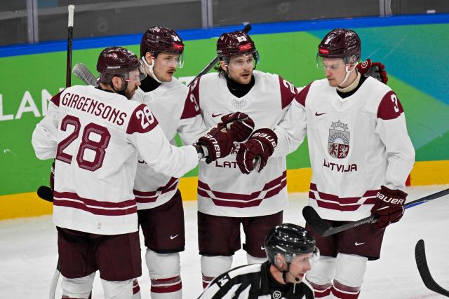 Latvia's #34 Eduards Tralmaks (2L) celebrates with teammates after scoring their first goal during the men's qualification play-off ice hockey match between Sweden and Latvia at the Milano Santagiulia Ice Hockey Arena during the Milano Cortina 2026 Winter Olympic Games in Milan, on February 17, 2026. (Photo by Alexander NEMENOV / AFP)