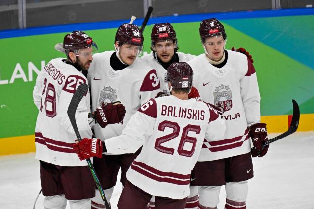 Latvia's #34 Eduards Tralmaks (2L) celebrates with teammates after scoring their first goal during the men's qualification play-off ice hockey match between Sweden and Latvia at the Milano Santagiulia Ice Hockey Arena during the Milano Cortina 2026 Winter Olympic Games in Milan, on February 17, 2026. (Photo by Alexander NEMENOV / AFP)