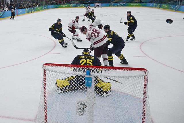 Latvia's #28 Zemgus Girgensons (C) vies for the puck with Sweden's #03 Oliver Ekman-Larsson during the men's qualification play-off ice hockey match between Sweden and Latvia at the Milano Santagiulia Ice Hockey Arena during the Milano Cortina 2026 Winter Olympic Games in Milan, on February 17, 2026. (Photo by Alexander NEMENOV / POOL / AFP)