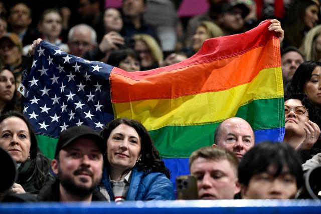 A fan holds a combination US and rainbow flag during the figure skating women's single skating short program during the Milano Cortina 2026 Winter Olympic Games at Milano Ice Skating Arena in Milan on February 17, 2026. (Photo by WANG Zhao / AFP)